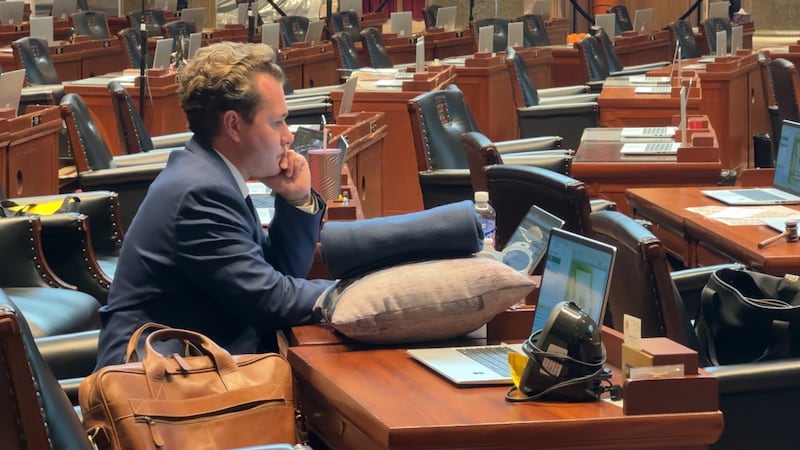 El representante Jeremy Dean, con una almohada y una manta sobre su escritorio, dispuesto a...
