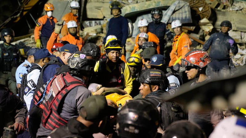 Rescue workers search through the rubble of a collapsed building after earthquake in Caracas,...